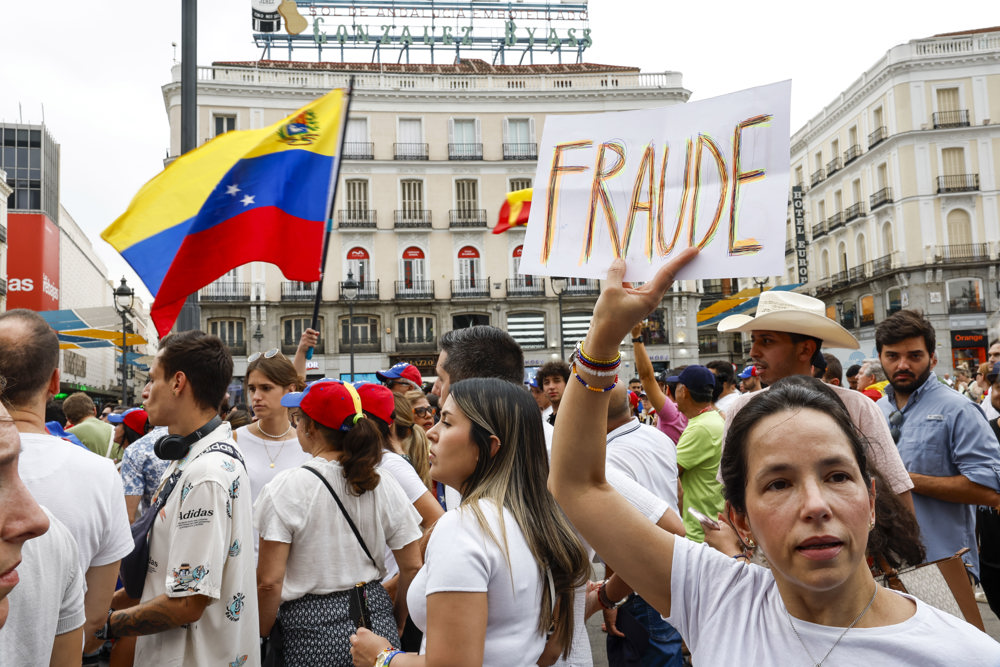 Uma mulher segura um cartaz na manifestação convocada pela oposição venezuelana um dia após as eleições no país, nesta segunda-feira em Madrid