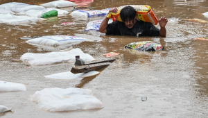 A man carrying a sack of flour wades through flood waters after the Bagmati River overflowed following heavy monsoon rains in Kathmandu on September 28, 2024. Floods and landslides caused by heavy downpours in Nepal killed at least 10 people across the Himalayan country, with rescue teams searching for 18 missing, a disaster official said on September 28.