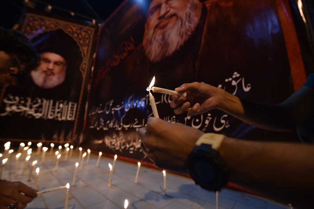 Manifestantes acendem velas em frente a fotos do falecido líder do Hezbollah, Hassan Nasrallah, durante um protesto anti-Israel após a morte de Nasrallah, em Carachi, Paquistão