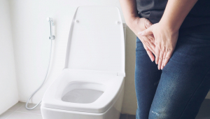 Mulher segurando a mão perto de vaso sanitário - conceito de problema de saúde