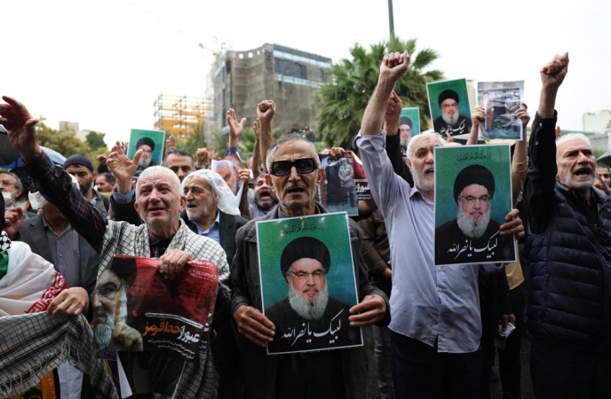 Manifestantes seguram fotos do falecido líder do Hezbollah, Hassan Nasrallah, durante um protesto anti-Israel na Praça Palestina, em Teerã