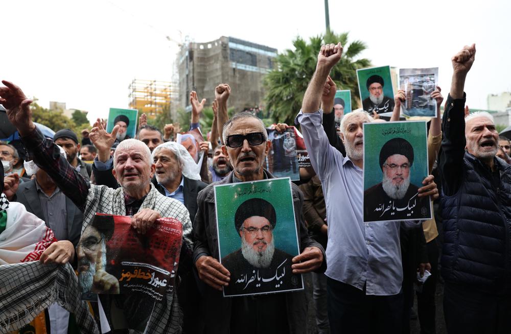 Manifestantes seguram fotos do falecido líder do Hezbollah, Hassan Nasrallah, durante um protesto anti-Israel na Praça Palestina, em Teerã