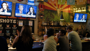 Pessoas sentam-se atrás de um bar enquanto participam de uma festa para assistir ao debate presidencial dos EUA entre a vice-presidente e candidata presidencial democrata Kamala Harris e o ex-presidente dos EUA e candidato presidencial republicano Donald Trump, no American Eat Co. em Tucson, Arizona