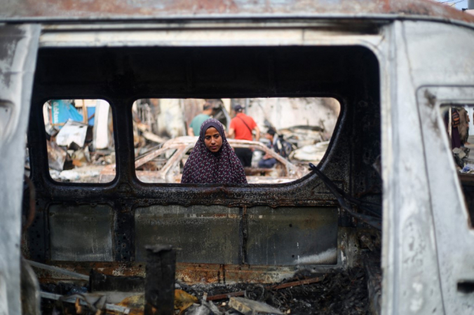 A Palestinian girl looks inside a cr carcass at the site of an Israeli airstrike on tents for displaced people two days earlier in the courtyard of Al-Aqsa Martyrs Hospital in Deir al-Balah in the central Gaza Strip, on October 16, 2024. A spokesman for the Palestinian Civil Defence in Gaza said the October 14 strike had killed four people and wounded many more, noting it was the seventh time an attack had hit the 