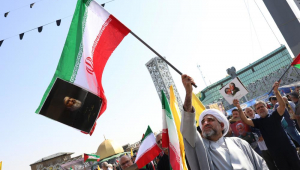 Um homem agita uma bandeira iraniana com uma foto do falecido líder do Hezbollah, Hassan Nasrallah