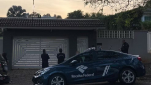 Agentes e carro da Receita em frente a uma casa