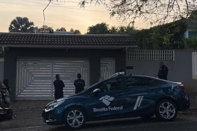 Agentes e carro da Receita em frente a uma casa