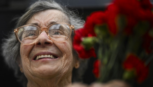 Celeste Caeiro, que entregou cravos vermelhos aos militares durante a Revolução dos Cravos em 25 de abril de 1974, segura um buquê de cravos durante um desfile militar em comemoração ao 50º aniversário da Revolução