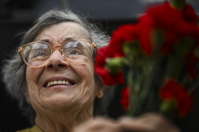 Celeste Caeiro, che consegnò garofani rossi ai militari durante la Rivoluzione dei garofani il 25 aprile 1974, tiene in mano un mazzo di garofani durante una parata militare per commemorare il 50° anniversario della Rivoluzione