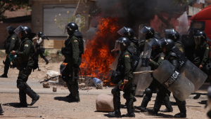 Membros da Polícia Boliviana caminham por uma estrada bloqueada e com pneus queimados por apoiadores de ex presidente Bolivia