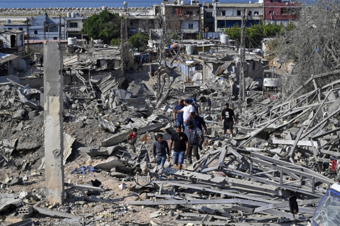 Pessoas inspecionam os danos no local de um ataque aéreo israelense na área de Ouzai, perto da pista do Aeroporto de Beirute, no sul da capital libanesa