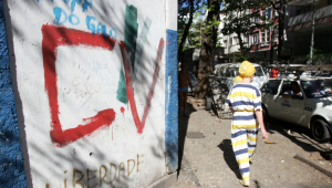 Popular passa diante de muro pichado com as iniciais do Comando Vermelho