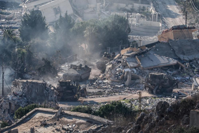 Blindados do exército israelense se movem entre casas destruídas na aldeia de Meiss El-Jabal, no sul do Líbano, enquanto deixam o território libanês