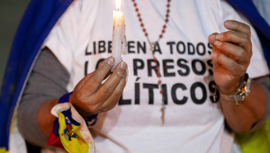 Uma mulher segura uma vela durante uma vigília pelos "presos políticos" na Universidade Central da Venezuela (UCV)