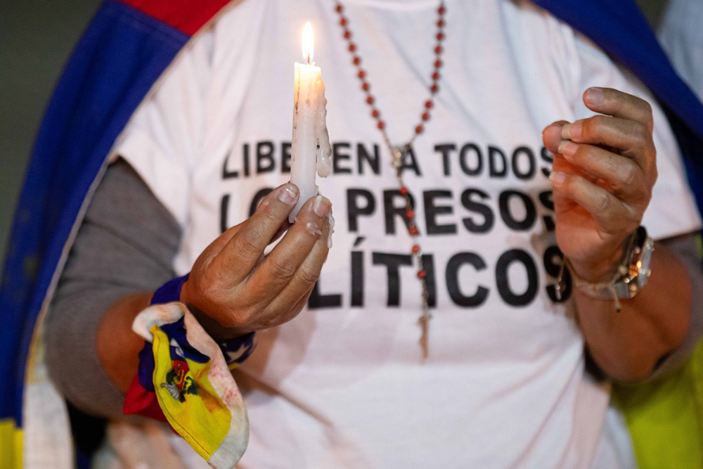 Uma mulher segura uma vela durante uma vigília pelos "presos políticos" na Universidade Central da Venezuela (UCV)