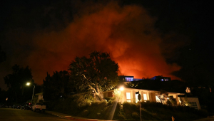 Fumaça e chamas do incêndio Palisades avançam atrás de uma casa na Corda Drive, em direção ao bairro de Encino, em Los Angeles