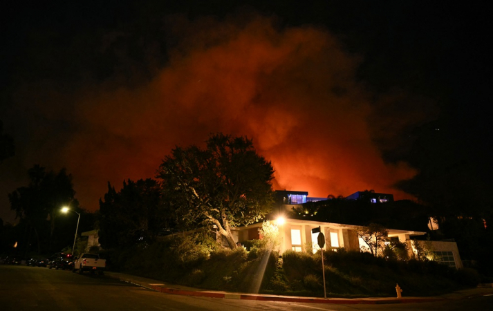 Fumaça e chamas do incêndio Palisades avançam atrás de uma casa na Corda Drive, em direção ao bairro de Encino, em Los Angeles