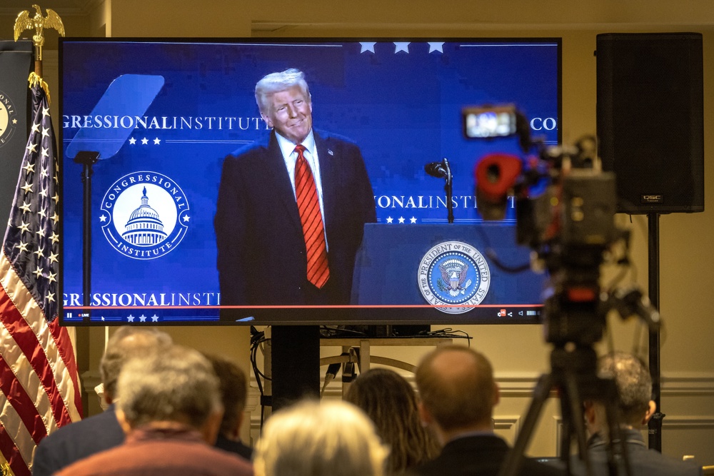 Membros da mídia acompanham em uma tela de TV o discurso do presidente dos Estados Unidos, Donald J. Trump, transmitido da sala de imprensa durante a Conferência Republicana de 2025 no resort Trump National Doral, em Miami, Flórida