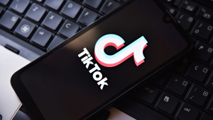 Celular com logo do TikTok em cima de teclado de notebook