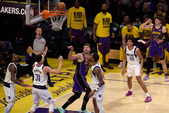 O armador do Los Angeles Lakers, Luka Dončić (C), arremessa a bola durante o primeiro tempo do jogo de basquete da NBA entre o Dallas Mavericks e o Los Angeles Lakers