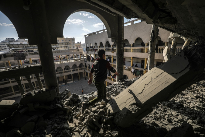 Um menino palestino inspeciona uma área destruída da escola Al Tabien após ataques aéreos israelenses em Gaza