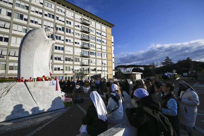 Fiéis rezam em frente à estátua do Papa João Paulo II na entrada do Hospital Gemelli, onde o Papa Francisco está internado, em Roma