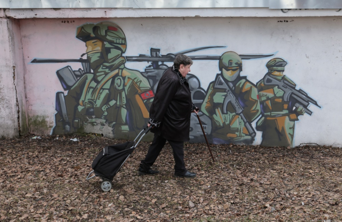 Uma mulher caminha em frente a um grafite que retrata soldados russos, criado pelo artista de rua russo Ivan Pimkin em apoio às Forças Armadas da Rússia, na cidade de Pavlovsky Posad, região de Moscou