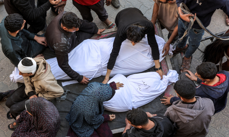 A woman sits by as a man places the shrouded body of one of the victims killed in Israeli bombardment in the bed of a horse-drawn cart at the Ahli Arab hospital, also known as the Baptist hospital, in Gaza City on March 18, 2025. Israel on March 18 unleashed its most intense strikes on the Gaza Strip since a January ceasefire, with rescuers reporting 220 people killed, and Hamas accusing Benjamin Netanyahu of deciding to