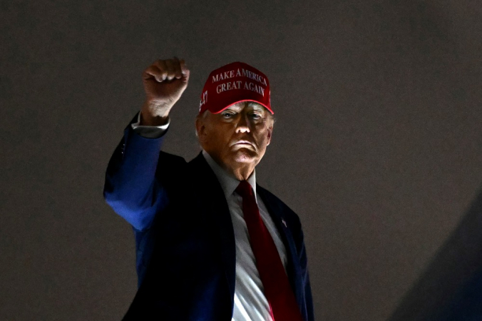 O presidente dos EUA, Donald Trump, ergue o punho ao embarcar no Air Force One