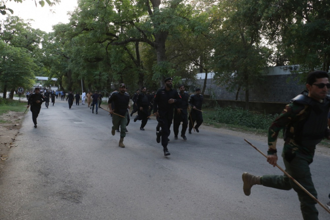 Agentes de segurança paquistaneses correm para se posicionar em frente ao Alto Comissariado da Índia enquanto apoiadores do partido político islâmico Pakistan Markazi Muslim League protestam contra a Índia, em Islamabad, capital do Paquistão