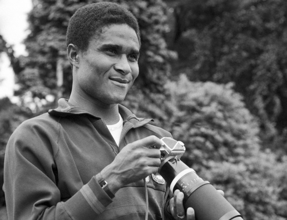 O jogador da seleção de Portugal, Eusebio da Silva Ferreira, segura uma câmera durante treino em Wilmslow, Cheshire, Inglaterra, durante o Campeonato Mundial de Futebol de 1966