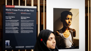 World Press Photo of 2025 award winner Palestinian photojournalist Samar Abu Elouf poses next to her winning photograph