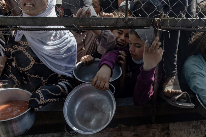Palestinos deslocados internamente aguardam do lado de fora de uma cozinha comunitria para receber pores limitadas de alimento, em meio  escassez de comida, em Khan Younis, sul da Faixa de Gaza,