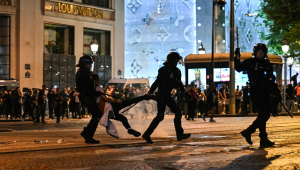 Policiais de choque detêm uma pessoa enquanto torcedores do Paris Saint-Germain comemoram a vitória do PSG na final da Liga dos Campeões da UEFA