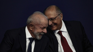 Geraldo Alckmin conta algo para Lula ao pé do ouvido; ambos estão rindo