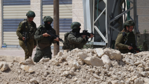Soldados israelenses fazem guarda enquanto palestinos tentam chegar às suas casas para cuidar de seus pertences no campo de refugiados de Tulkarem