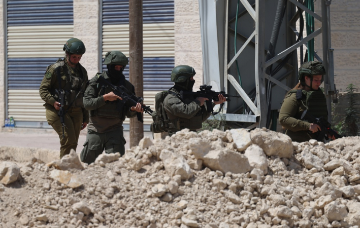 Soldados israelenses fazem guarda enquanto palestinos tentam chegar às suas casas para cuidar de seus pertences no campo de refugiados de Tulkarem