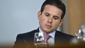 Hugo Motta aparentemente pensativo, sentado em frente a uma mesa no Palácio do Planalto