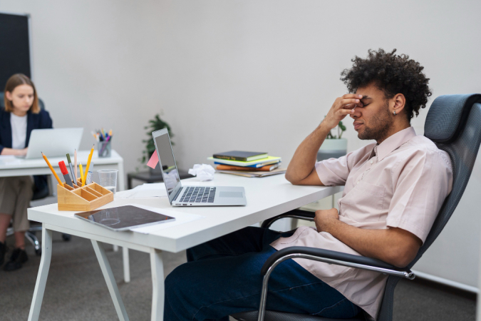Homem cansado com laptop no trabalho