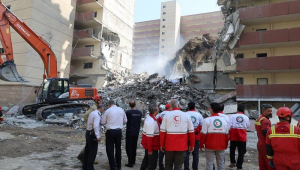 Voluntários do Crescente Vermelho Iraniano se reúnem em frente a um prédio destruído por um ataque israelense em Teerã