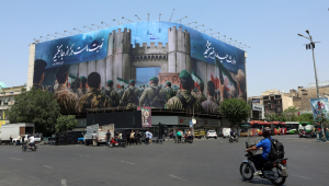 Iranianos passam de carro por um outdoor anti-Israel em um prédio, com os dizeres “Agora é a nossa vez”