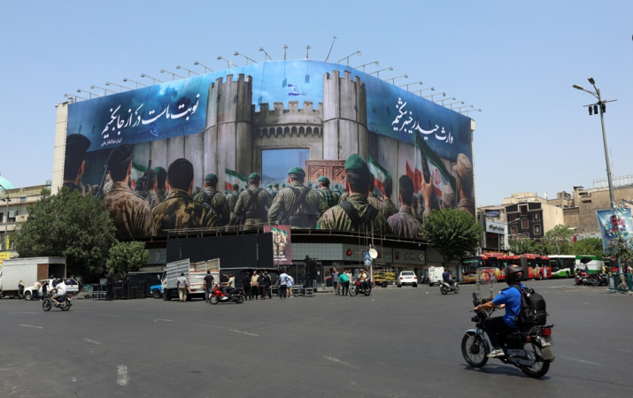 Iranianos passam de carro por um outdoor anti-Israel em um prédio, com os dizeres “Agora é a nossa vez”