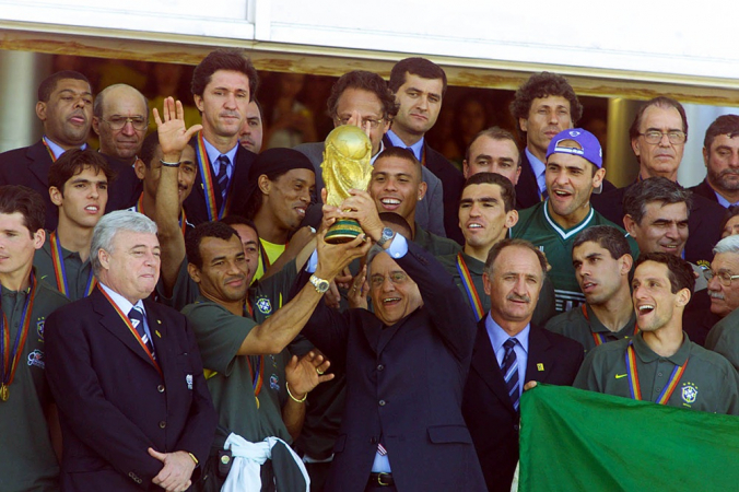 O capitão da Seleção Brasileira, Cafu, e o Presidente do Brasil, Fernando Henrique Cardoso, levantam a taça juntos sob os olhares dos jogadores e da comissão técnica do Brasil, além do presidente da CBF (Confederação Brasileira de Futebol) Ricardo Teixeira