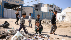 Crianças brincam perto do lixo em frente à sede fechada da agência da ONU para refugiados palestinos (UNRWA), na Cidade de Gaza, em 20 de maio de 2025, em meio à guerra em curso entre Israel e o movimento militante palestino Hamas. Israel, impulsionando uma ofensiva militar recentemente expandida na Faixa de Gaza, tem enfrentado crescente pressão, inclusive de um dos principais apoiadores, os Estados Unidos, para pôr fim ao bloqueio de ajuda humanitária imposto em 2 de março. (Foto de Bashar TALEB / AFP)