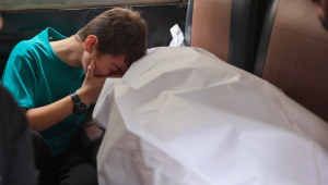 Um jovem palestino lamenta o corpo de um homem morto um dia antes enquanto tentava obter ajuda em um ponto de distribuição perto da passagem de fronteira de Zikim, controlada por Israel, durante seu funeral no hospital Al-Shifa, na Cidade de Gaza, em 23 de junho de 2025. (Foto de Omar AL-QATTAA / AFP)