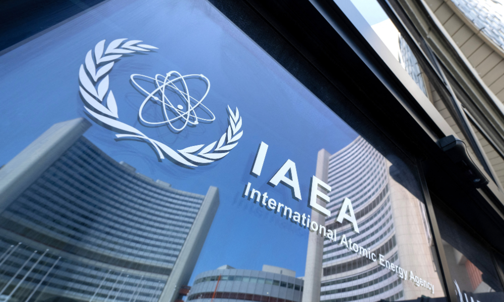 Prédios da sede da Agência Internacional de Energia Atômica (AIEA) refletidos nas portas com o logotipo da agência durante a reunião do Conselho de Governadores da AIEA em Viena, Áustria, em 13 de junho de 2025, onde o chefe da AIEA, Rafael Grossi, informou os membros do conselho sobre os ataques israelenses ao Irã, incluindo à instalação de enriquecimento de urânio de Natanz. (Foto de Joe Klamar / AFP)