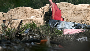 FOTOGRAFIA PRINCIPAL - Um policial monta guarda perto dos destroços do voo 171 da Air India após a queda em uma área residencial perto do aeroporto de Ahmedabad em 13 de junho de 2025. Equipes de resgate com cães farejadores vasculharam o local do acidente em 13 de junho de um jato de passageiros com destino a Londres que caiu em uma área residencial da cidade de Ahmedabad, na Índia, matando pelo menos 265 pessoas a bordo e no solo. (Foto de Punit PARANJPE / AFP)