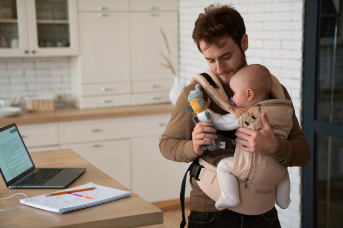 Pai de tiro médio trabalhando enquanto segura o bebê