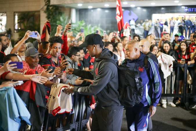 O zagueiro Léo Pereira tira fotos com torcedores na chegada do Flamengo a Santos