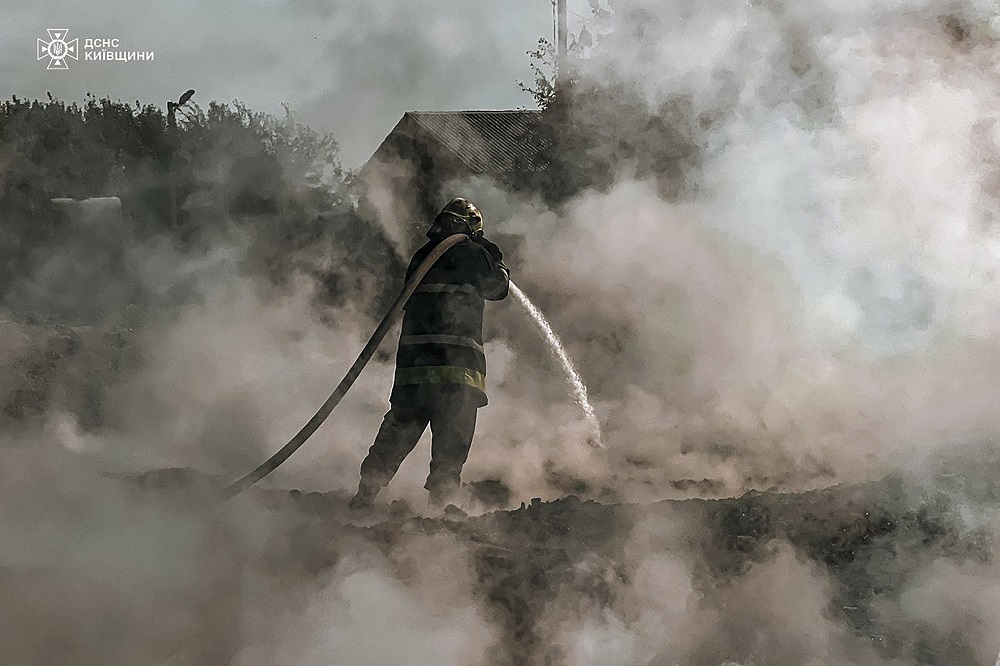 bombeiro apagando um incêndio após um ataque russo na região de Kiev